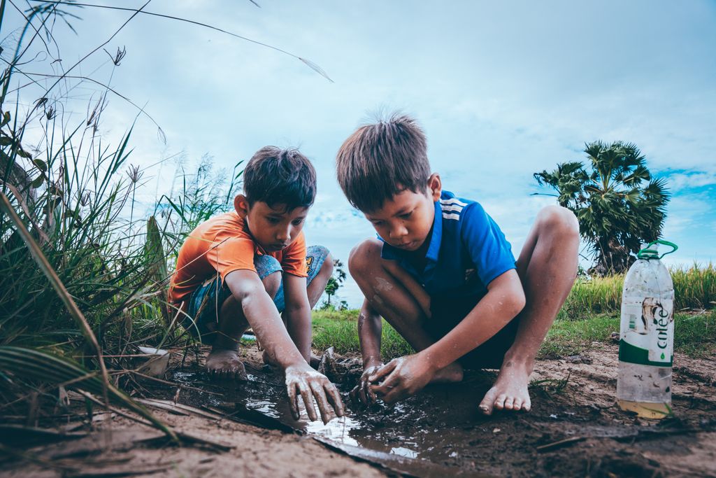 earth endotoxin Two boys enjoying playing in a muddy puddle, depicting outdoor play and childhood exploration.