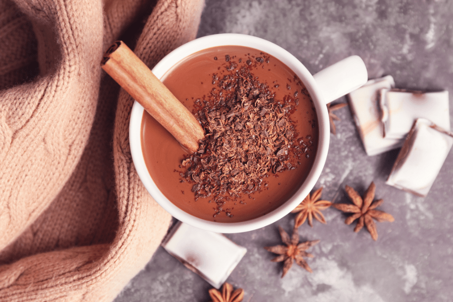 mug of hot cocoa with stick of cinnamon, star anise and chocolate shavings