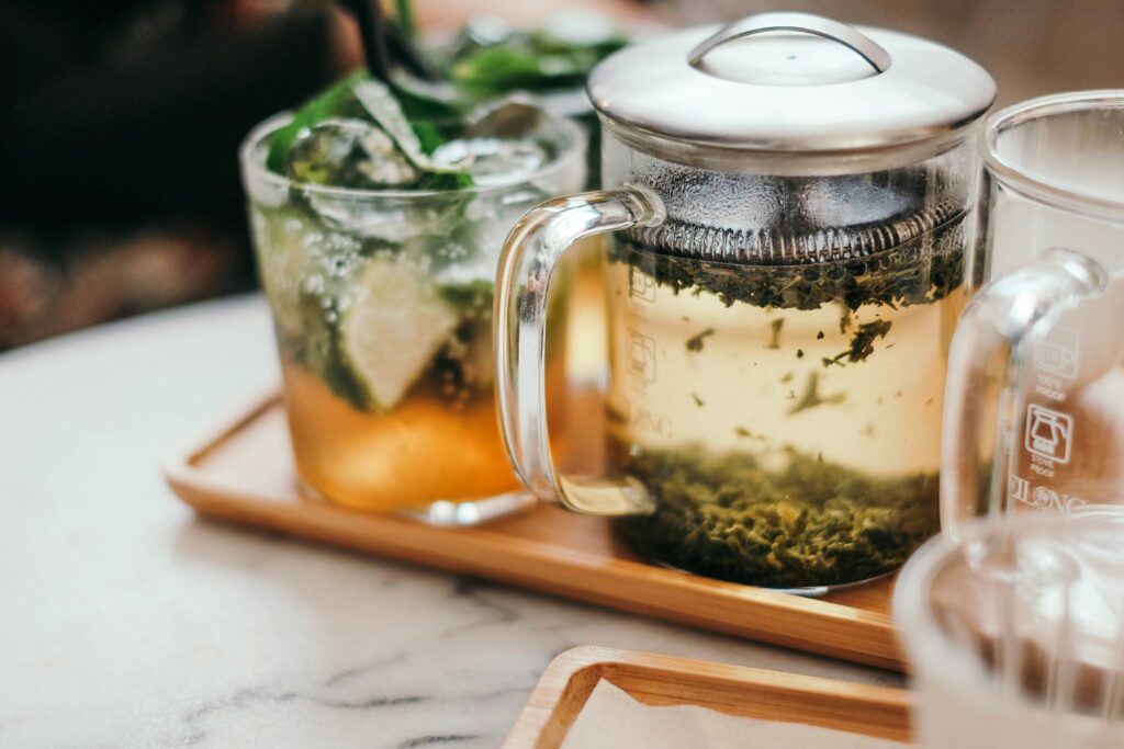 glass teapot with glasses of tea and peppermint sprigs