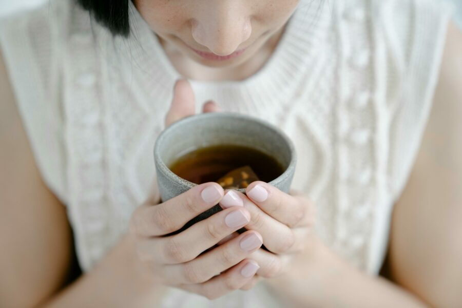 a cup of stomach soothing herbal tea with woman holding cup