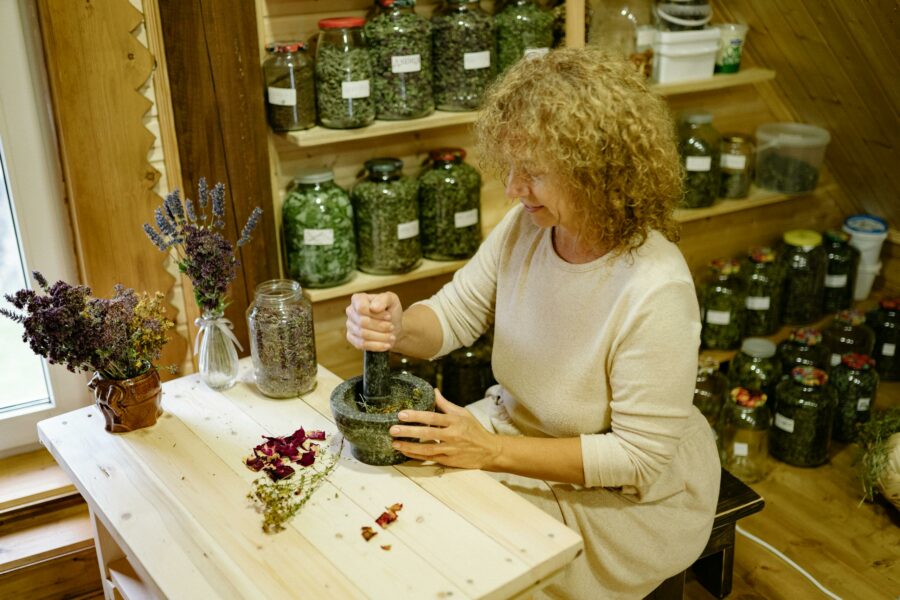 essential medicinal herbs being pounded in mortar with pestle by woman